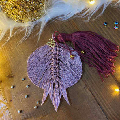 Χειροποίητο μακραμέ γούρι 2026 σε ροζ μεταλλιζέ με βουργουνδί φούντα και χρυσό “2026”, από το Capricorn Creations.