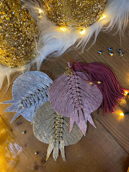 Χειροποίητο μακραμέ γούρι 2026 σε ροζ μεταλλιζέ με βουργουνδί φούντα και χρυσό “2026”, από το Capricorn Creations.