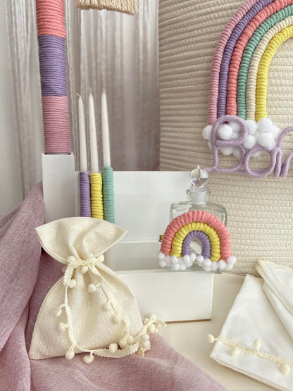 Decorative items including a rainbow-themed bottle and a drawstring bag on a textured surface.